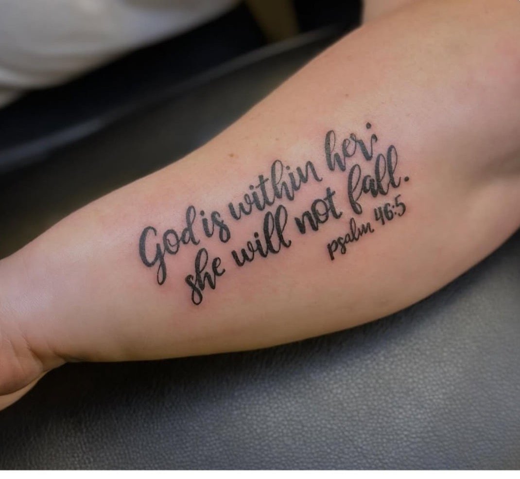 Cursive script tattoo reading a scripture verse along an inner forearm
